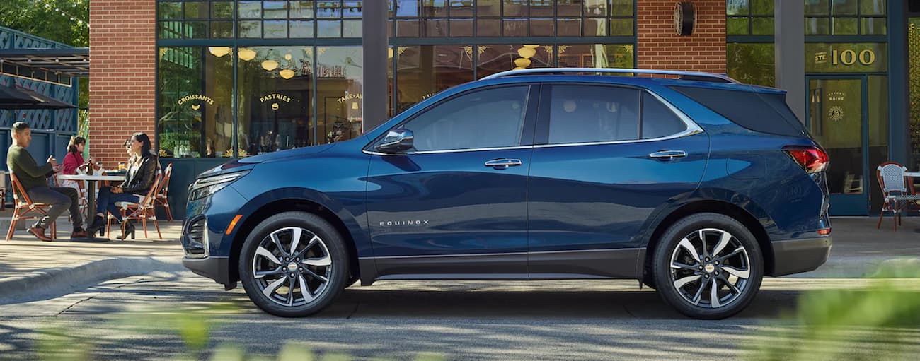 A blue 2022 Chevy Equinox is shown from the side parked in front of a modern house.
