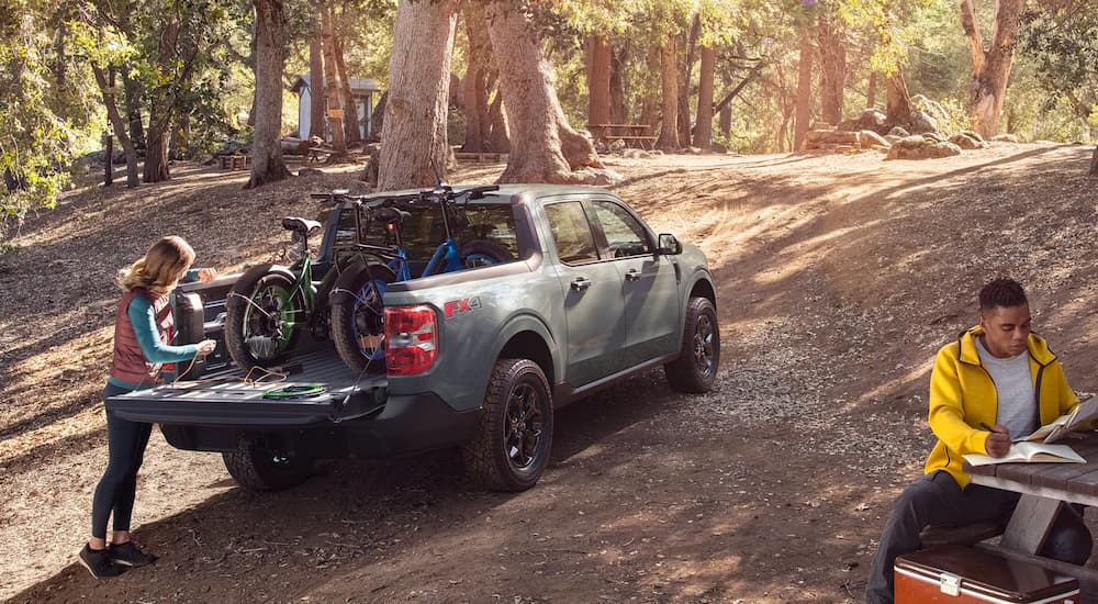 A grey 2022 Ford Maverick is shown with bikes in the bed at a campsite.