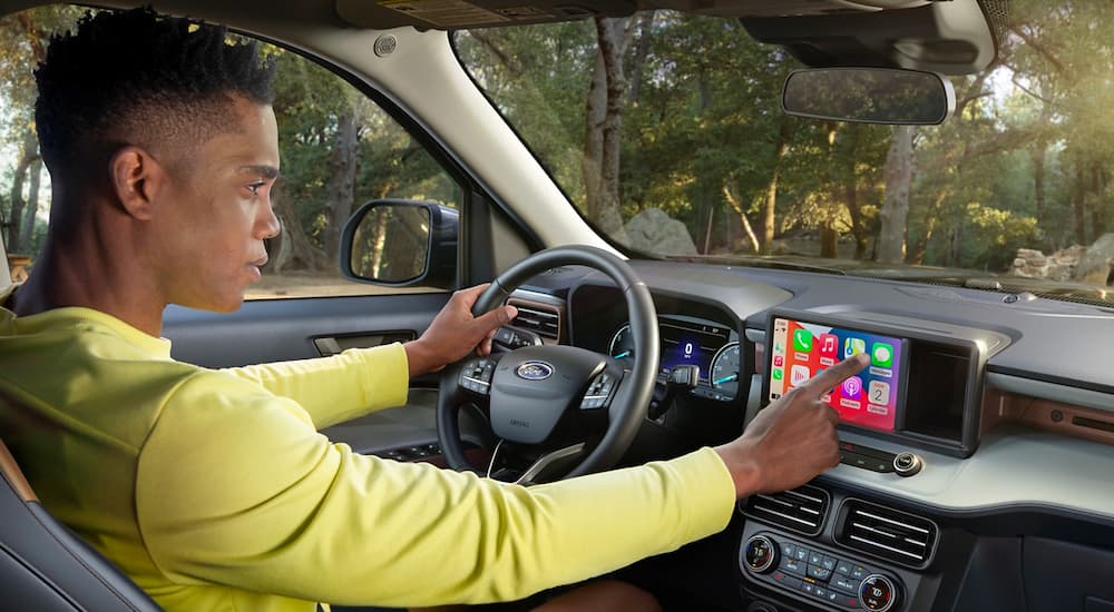 A man in a yellow shirt is using the touchscreen infotainment screen in a 2022 Ford Maverick.