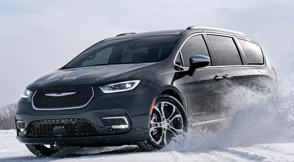 A black 2021 Chrysler Pacifica is driving through a snow covered field.