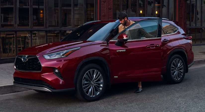 A person is shown getting into a red 2020 Toyota Highlander Hybrid.