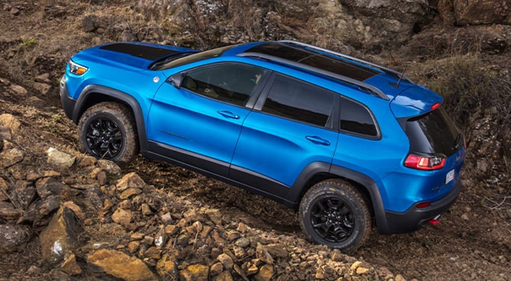 A blue 2020 Jeep Cherokee is shown off-roading in the mountains.