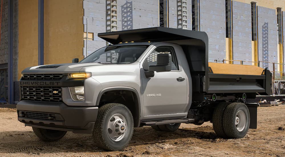 A silver 2022 Chevy Silverado 3500 HD is shown at a construction site.