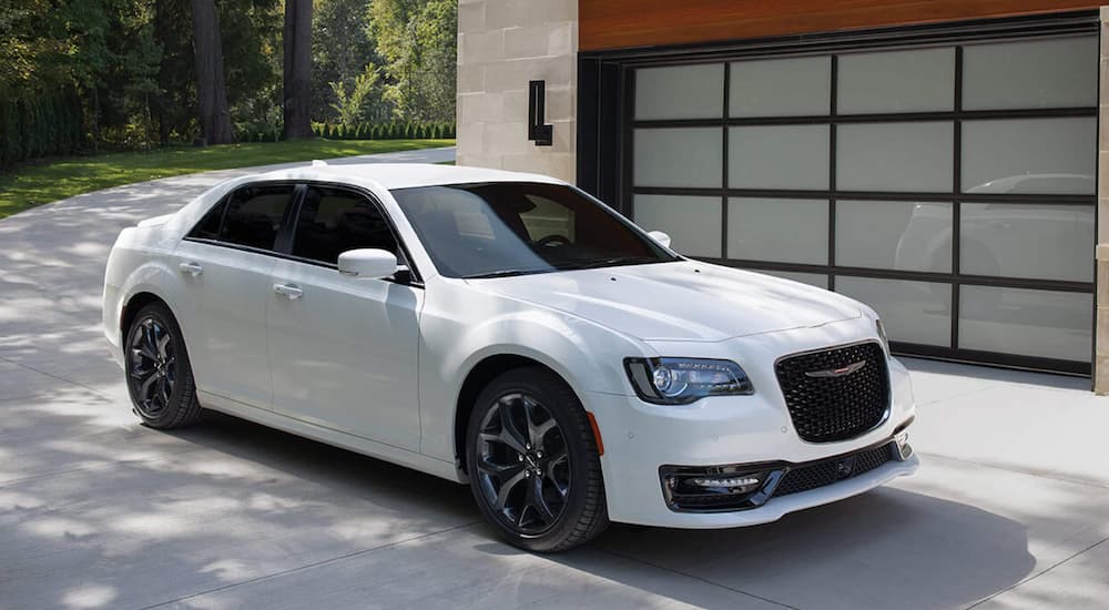 A white 2021 Chrysler 300 is shown parked in front of a modern house.
