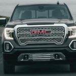 A grey 2021 GMC Sierra 1500 Denali is shown from the front driving down the road after leaving a GMC truck dealership.