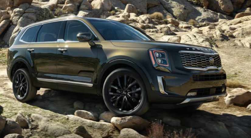 A green 2021 Kia Telluride is off-roading in the mountains.