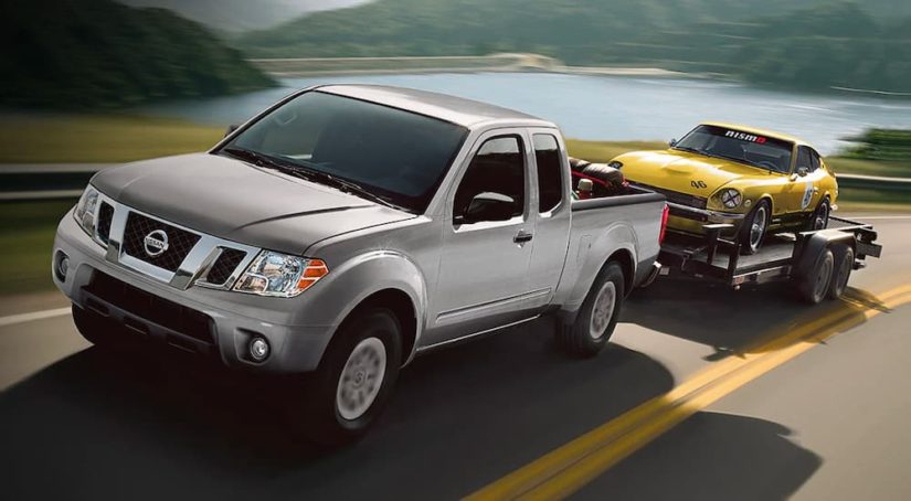 A silver 2019 Nissan Frontier is shown towing a car after leaving a used truck dealer.