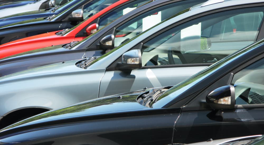 A close up shows a row of cars at a used car lot.