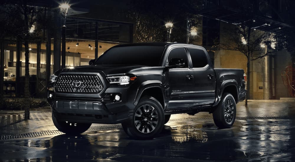 A black 2021 Toyota Tacoma is shown from the side parked on a city street at night.