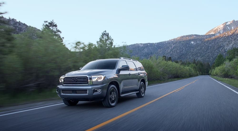 A grey 2021 Toyota Sequoia TRD Sport is shown driving down an empty road.