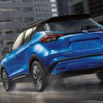 A blue 2021 Nissan Kicks is shown from the rear driving through a city.