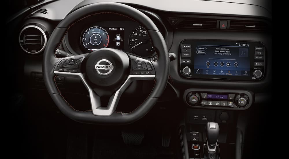 The interior of a 2021 Nissan Kicks shows the steering wheel and infotainment screen.