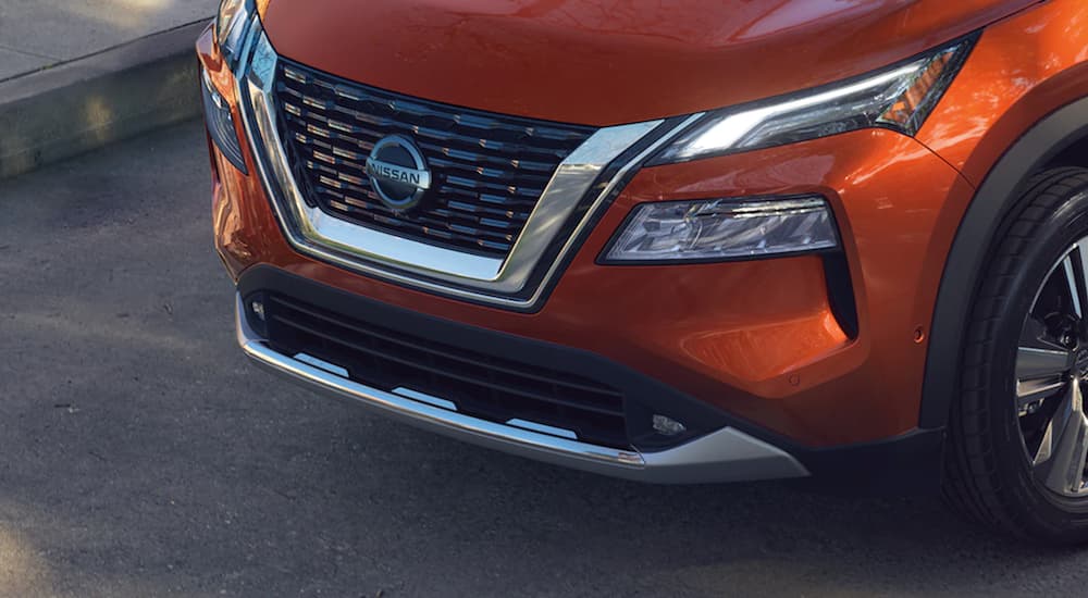 An orange 2021 Nissan Rogue shows the grille in close up.