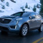 A grey 2022 Cadillac XT5 is shown driving down a snowy road.