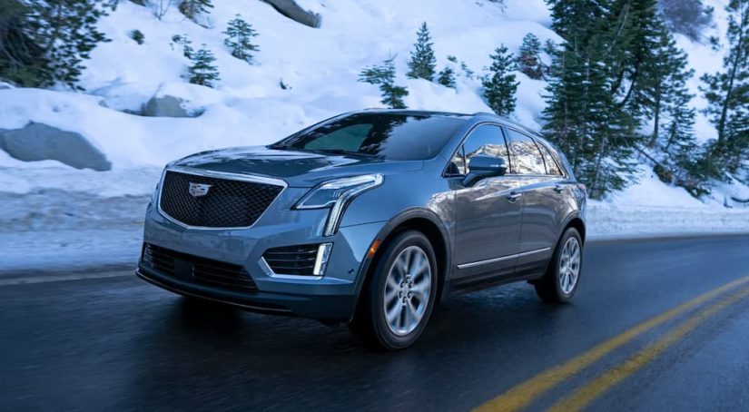 A grey 2022 Cadillac XT5 is shown driving down a snowy road.