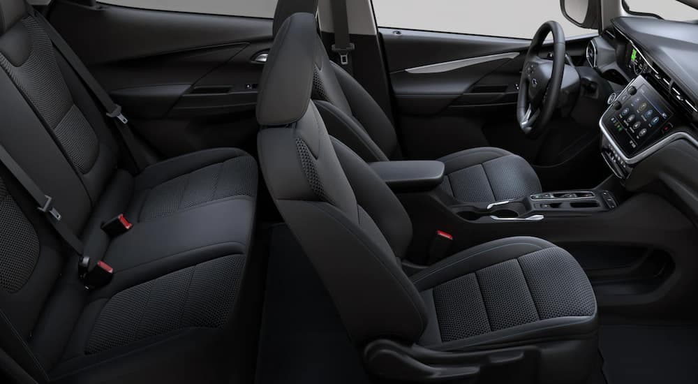 The black interior of a 2022 Chevy Bolt EV shows two rows of seating and the steering wheel.