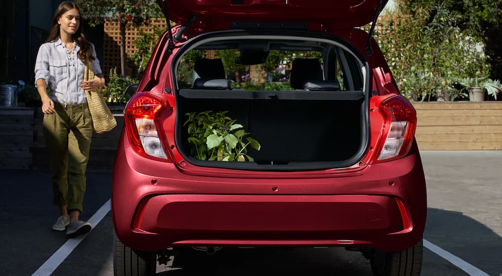 A red 2022 Chevy Spark is shown with an open lift-gate and plants in the back.