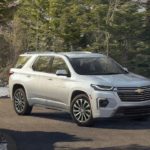 A white 2022 Chevy Traverse is shown parked in front of a forest.