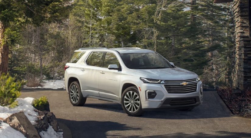 A white 2022 Chevy Traverse is shown parked in front of a forest.