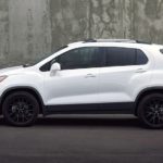 A white 2022 Chevy Trax is shown from the side parked in front of a cement wall.