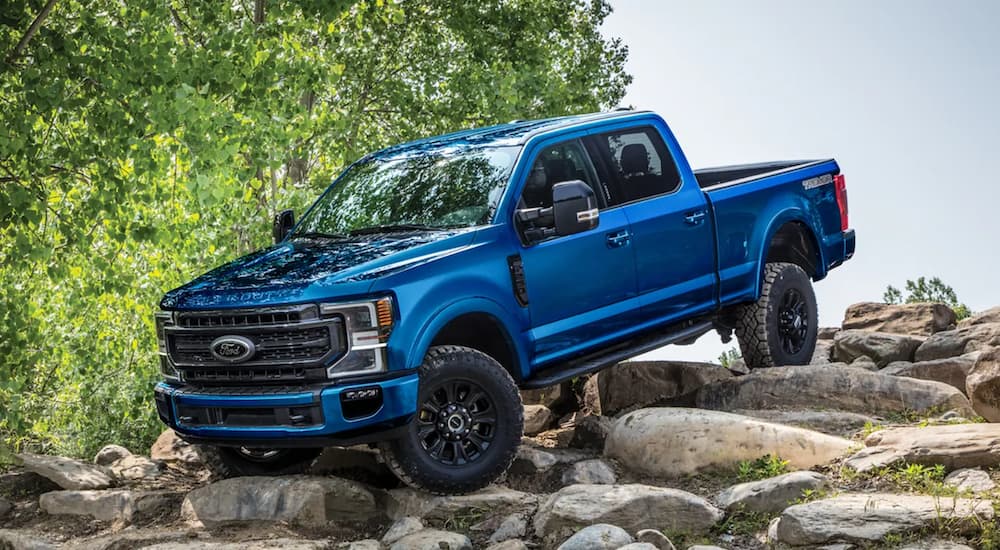 A blue 2022 Ford Super Duty is shown parked on a rock pile in the mountains.