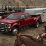 A red 2022 Ford Super Duty is shown towing a closed trailer on a cow farm.