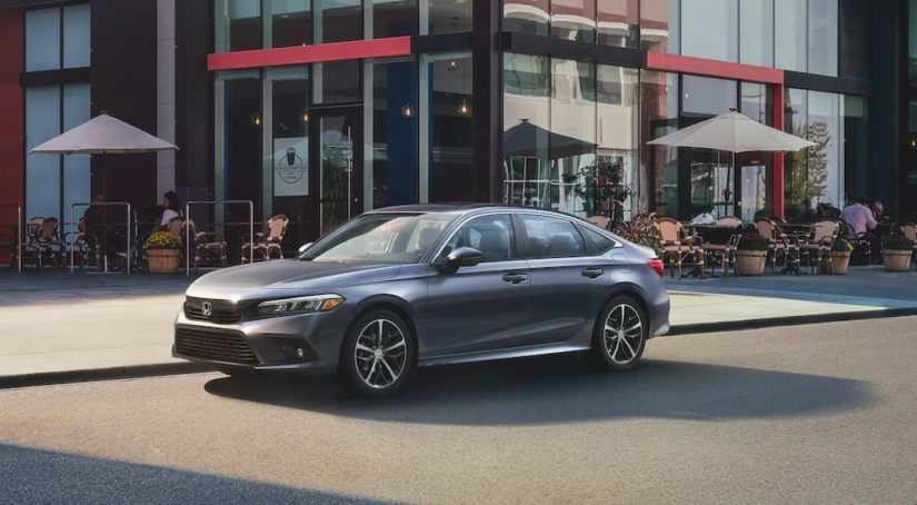 A grey 2022 Honda Civic Touring Sedan is shown parked in front of a coffee shop.
