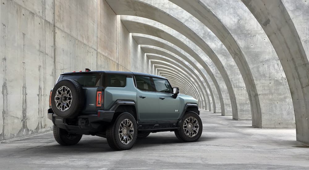 A green 2024 GMC Hummer EV SUV is shown parked under a concrete archway.