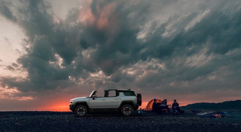 A white 2024 GMC Hummer EV SUV is shown from the side at sunset.