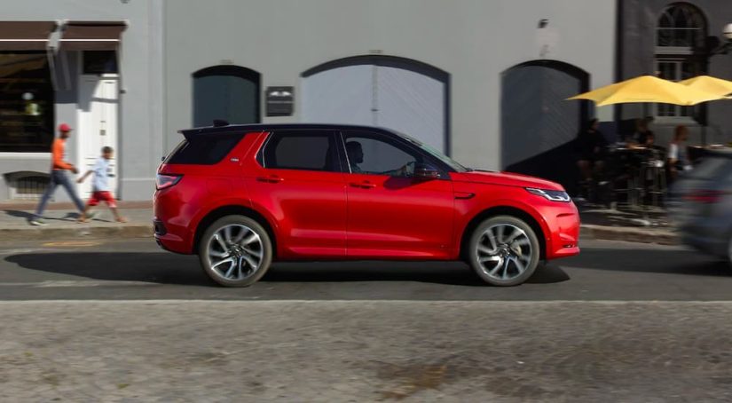 A red 2022 Land Rover Discovery Sport is shown from the side driving in a city.