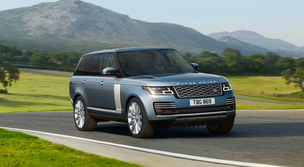 A blue 2022 Range Rover is shown driving past a field.