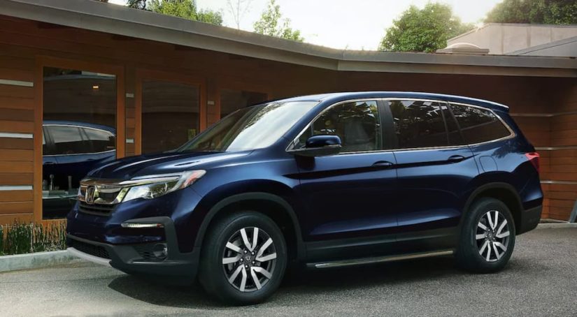 A blue 2021 Honda Pilot EX-L is shown parked in front of a modern house.