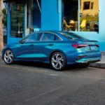 A blue 2022 Audi A3 is shown parked outside of a corner shop.