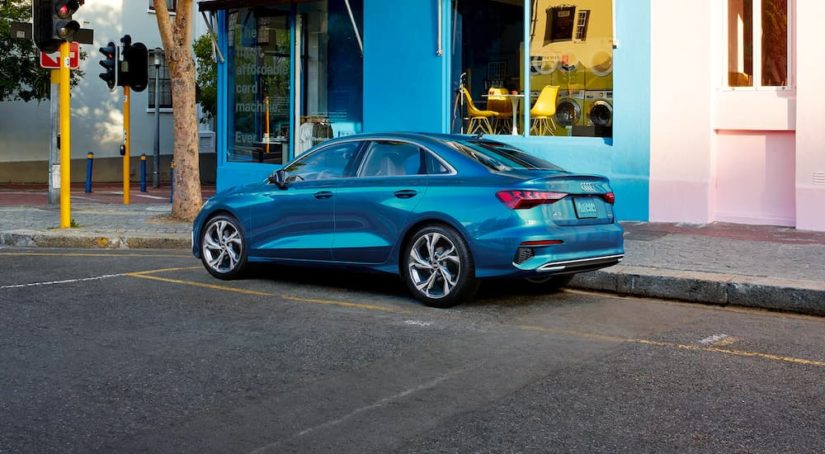 A blue 2022 Audi A3 is shown parked outside of a corner shop.