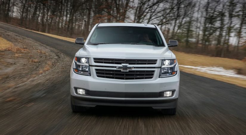 A white 2019 Chevy Tahoe RST is shown from the front driving on an empty road.