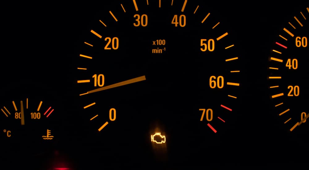 A gauge cluster is shown with a check engine light illumintaed.