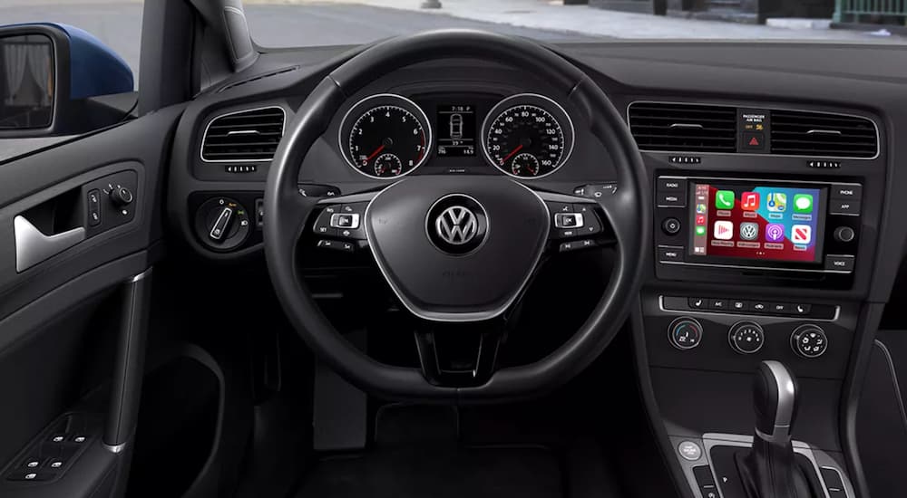 The interior of a 2021 Volkswagen Golf shows the steering wheel and infotainment screen.