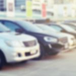 A row of cars is shown at a used car dealer.