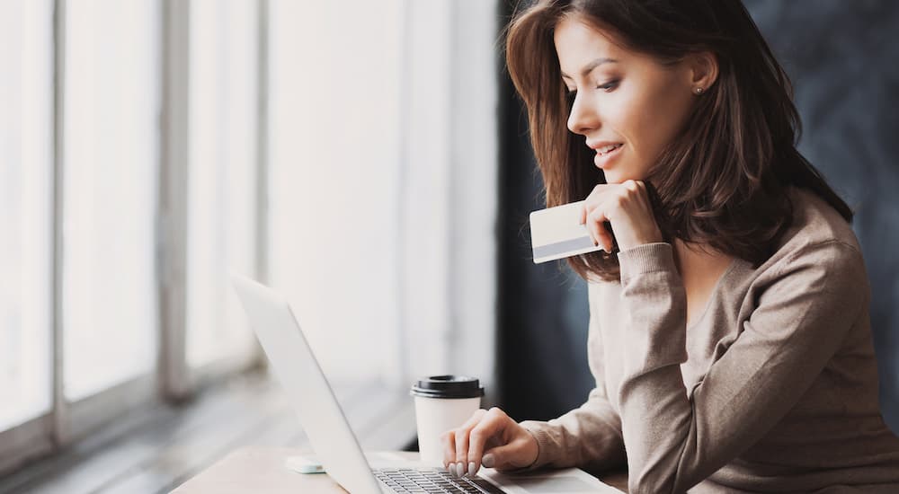 A woman is online shopping while holding a credit card.