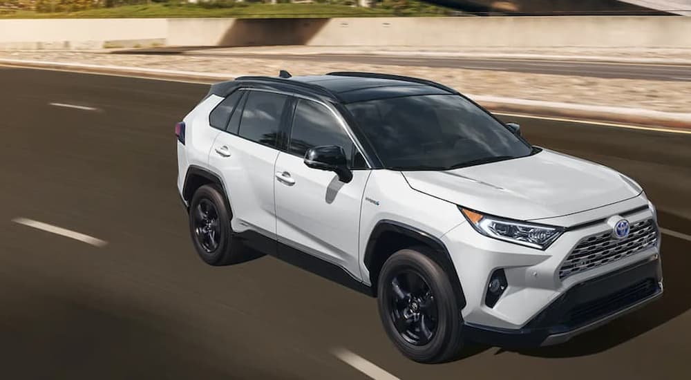 A white 2020 Toyota RAV4 Hybrid is shown driving on a highway.
