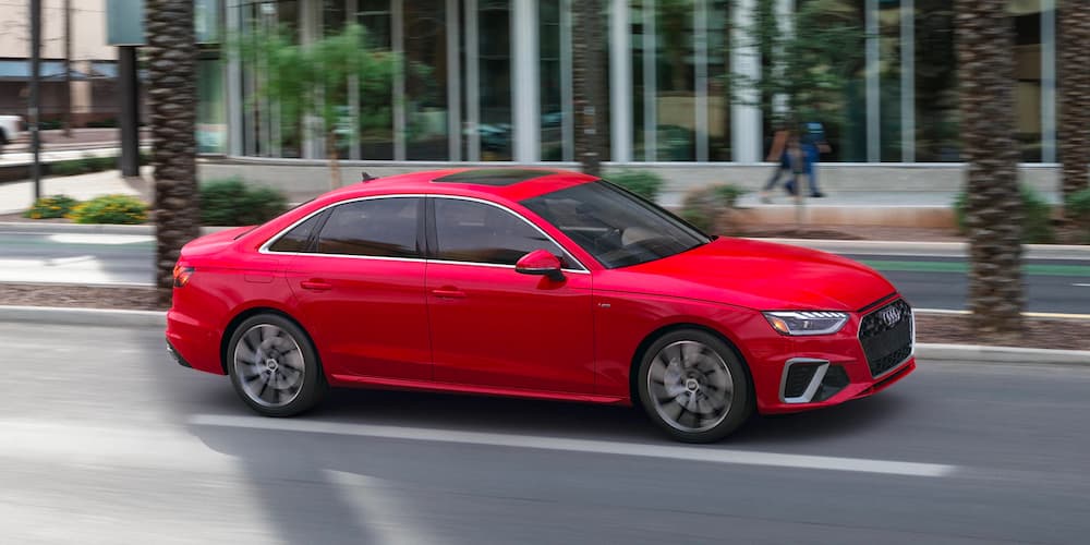 A red 2021 Audi A4 is shown driving on a city street.
