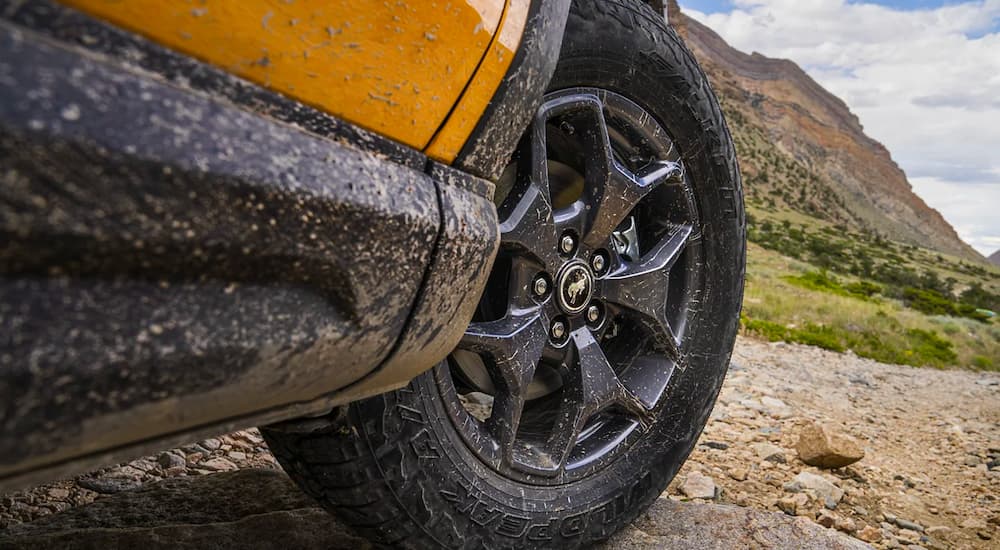 A close up shows the black alloy wheel on a yellow 2021 Ford Bronco Sport Badlands.