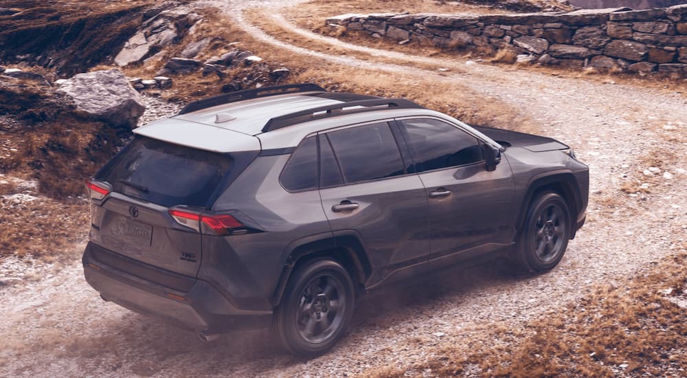 A green 2021 Toyota RAV4 is shown driving on a dirt road.