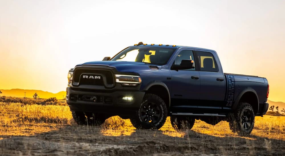 A blue 2021 Ram 2500 is shown from the side parked in a field at sunset.