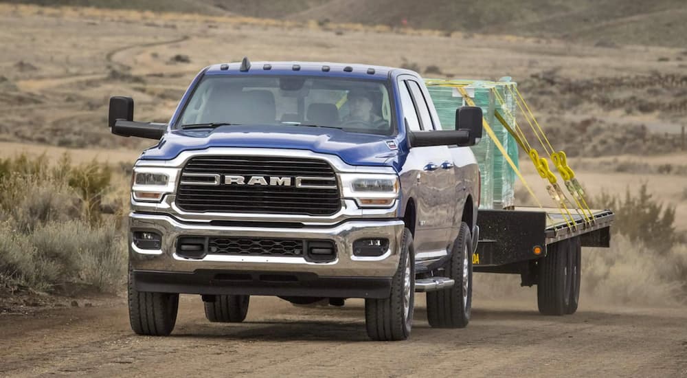 A blue 2021 Ram 2500 is shown from the front towing a tailor.