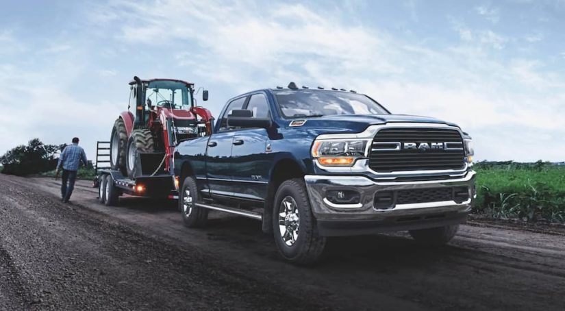 A blue 2021 Ram 2500 is shown from the front towing a tractor.