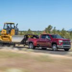 A red 2022 Chevy Silverado 3500HD is shown towing a trailer and bulldozer.