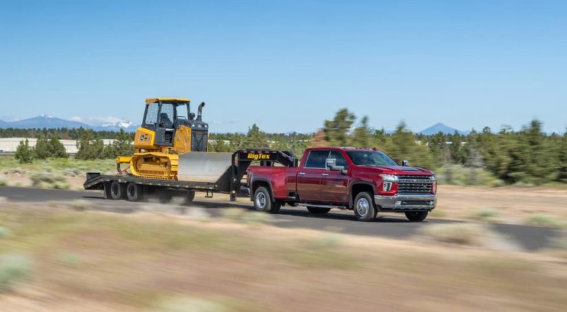 A red 2022 Chevy Silverado 3500HD is shown towing a trailer and bulldozer.