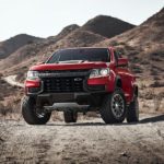 A red 2022 Chevy Colorado ZR2 is shown on a desert road after looking for Chevy lease deals.