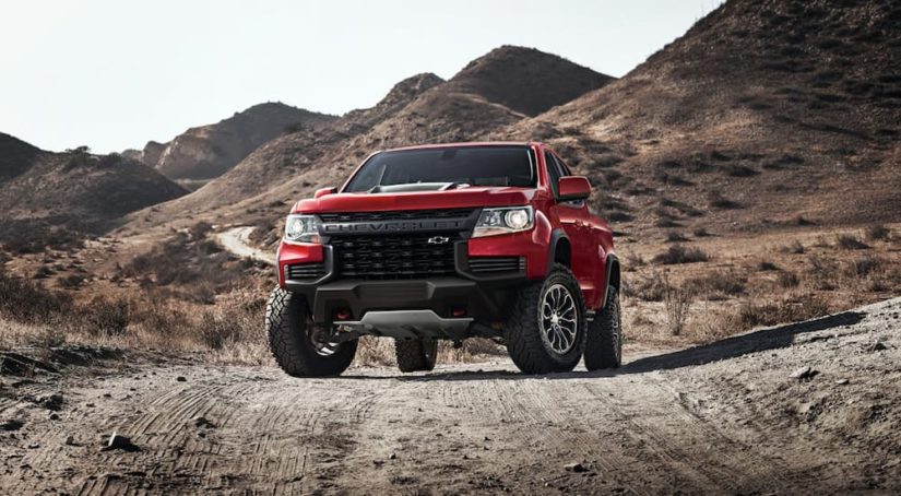 A red 2022 Chevy Colorado ZR2 is shown on a desert road after looking for Chevy lease deals.